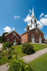 A historic brick church under a sunny blue sky