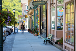 A person window shops along a row of stores on a sunny summer day.