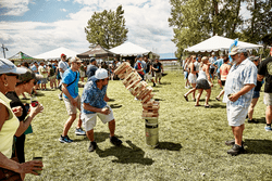 A group of people play yard games outside on a sunny day.