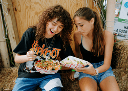 Two people enjoy a meal outdoors on a sunny day.