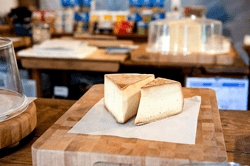 Two wedges of cheese on a square of parchment paper on a butcher block.