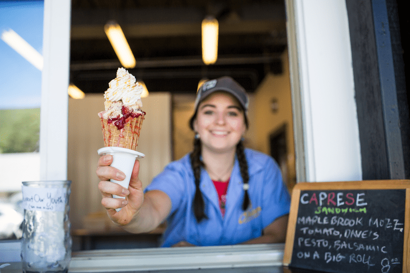 A person hands an ice cream cone from a window.