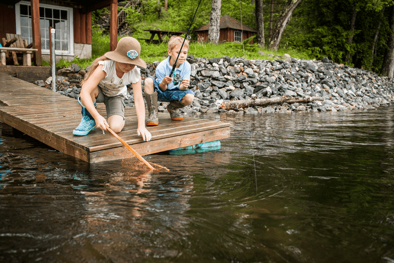 Two children fish from a small body of water.