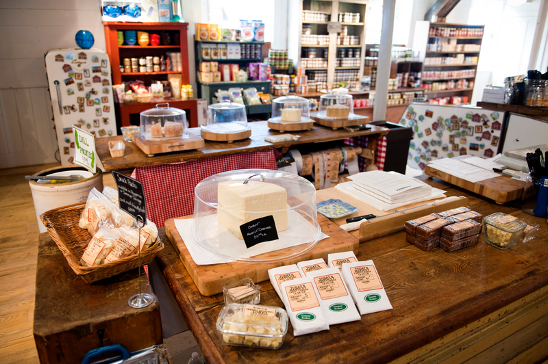 Various cheeses arrayed on a brown wooden table in a store.