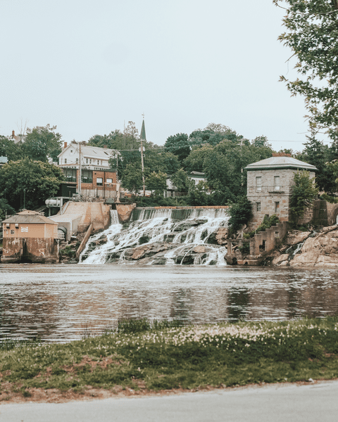 Water falls from a dam in a historic downtown in summer.