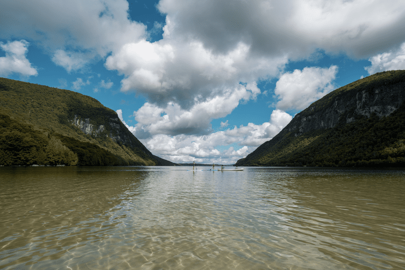 A lake with two tall mountains rising on either side in the image’s background.