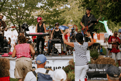 People gather in a field in early fall to listen to live music. Some are dancing.