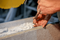 A hand holding a tool works to carve stone in an indoor studio.