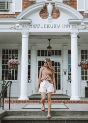 A person walks out of a large white building with a sign that reads Middlebury Inn.