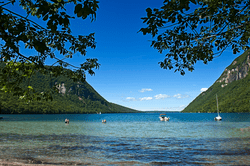 Boats float on a lake in between two mountains.