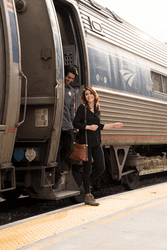 A person gets off a train on a sunny day.