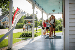 A group of people walk up a porch of an ice cream shop on a sunny day.