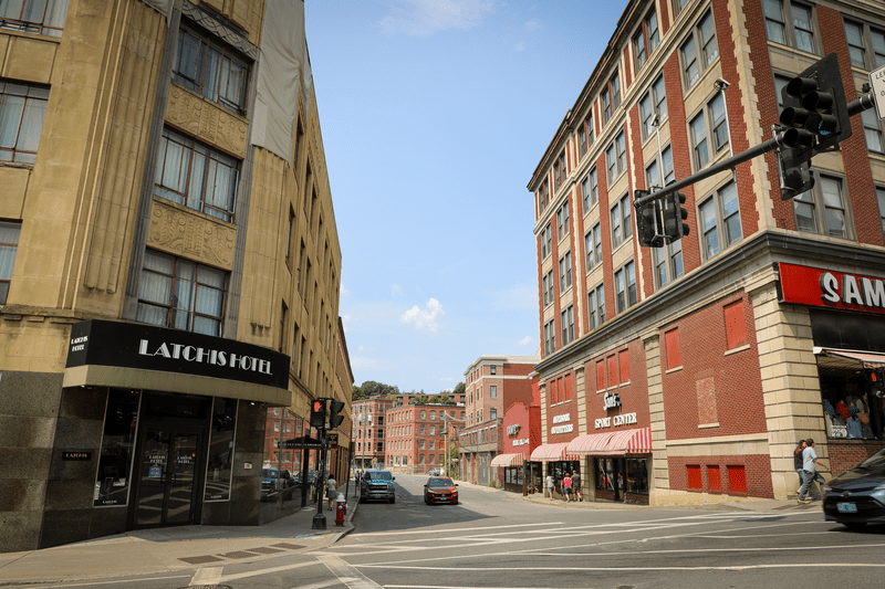 Two historic buildings on either side of a street. One reads Latchis Hotel in an art deco font.