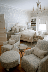 A large room at an inn with two armchairs and a bed.