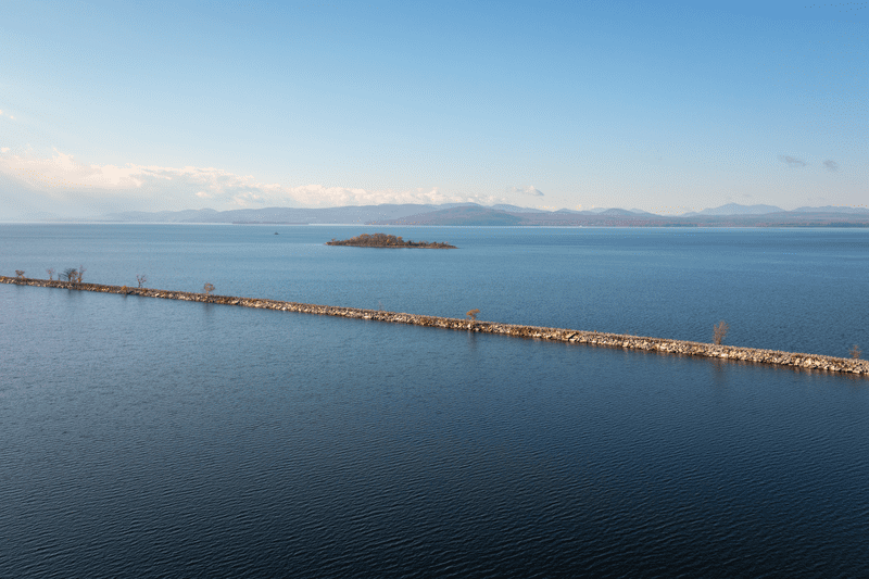 A jetty crosses Lake Champlain. An island appears in the distance.