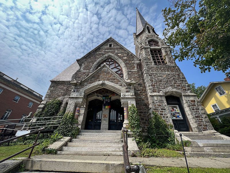 View looking up at a large stone church in the summer.