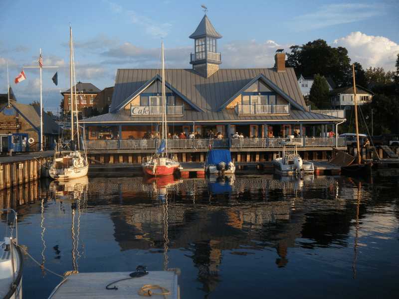 Sailboats are docked in a calm harbor on a warm day.