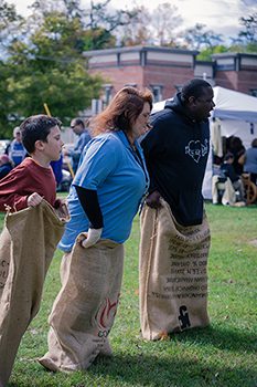 Three people hop across a lawn in sacks.