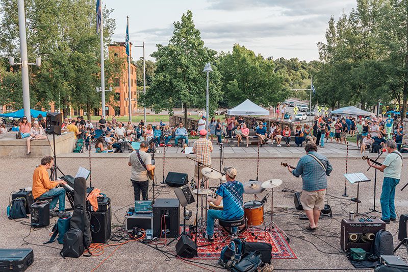 A group of musicians play in front of a crowd at an outdoor performance.