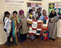 A group of people show a weaved blanked in a museum.