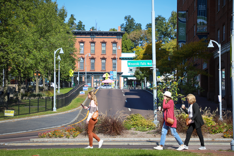 People walk along a sidewalk on a sunny day.