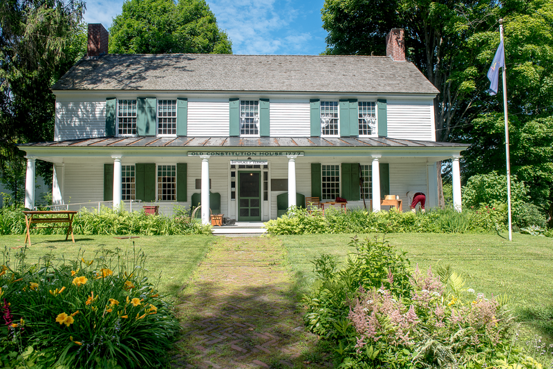 A white historic building in the summer seen from outside.