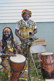 Two people play instruments outdoors.