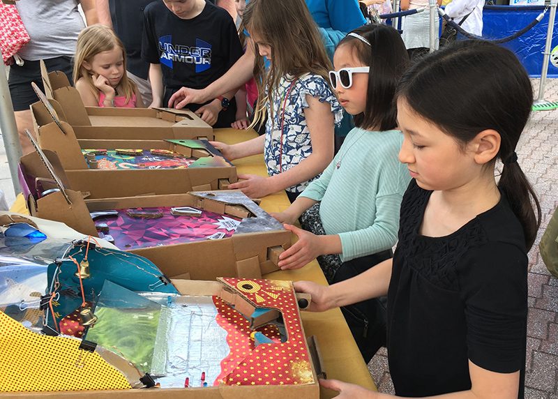 Children sit at a table doing arts and crafts.