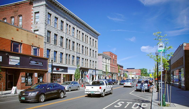 Building line a town street with cars on a sunny, warm day.