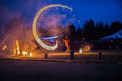 A performance takes place next to an outdoor fire at night.