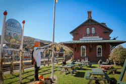 A red brick building in front of an outdoor lawn with picnic tables and a Chef's Market sign.