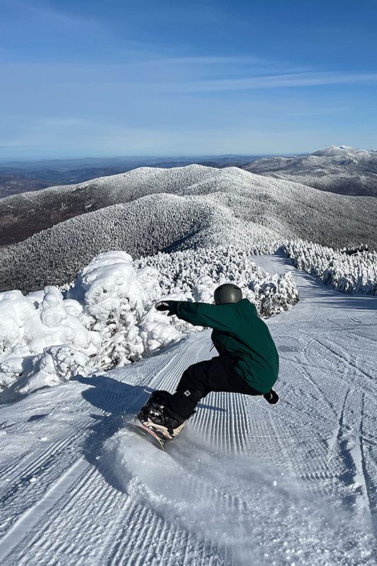 Seen from behind, a person snowboards down a snowy mountain.